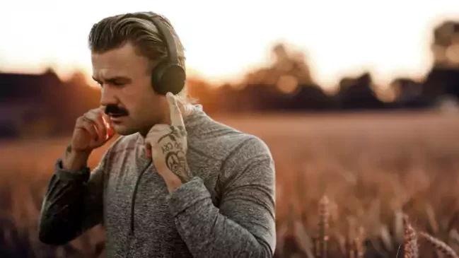 handsome man wearing wireless headphones with nature view remixed media